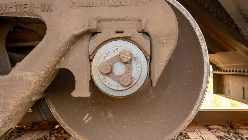 Close-up of a freight wagon wheelset and axle-box bearing assembly on the rail